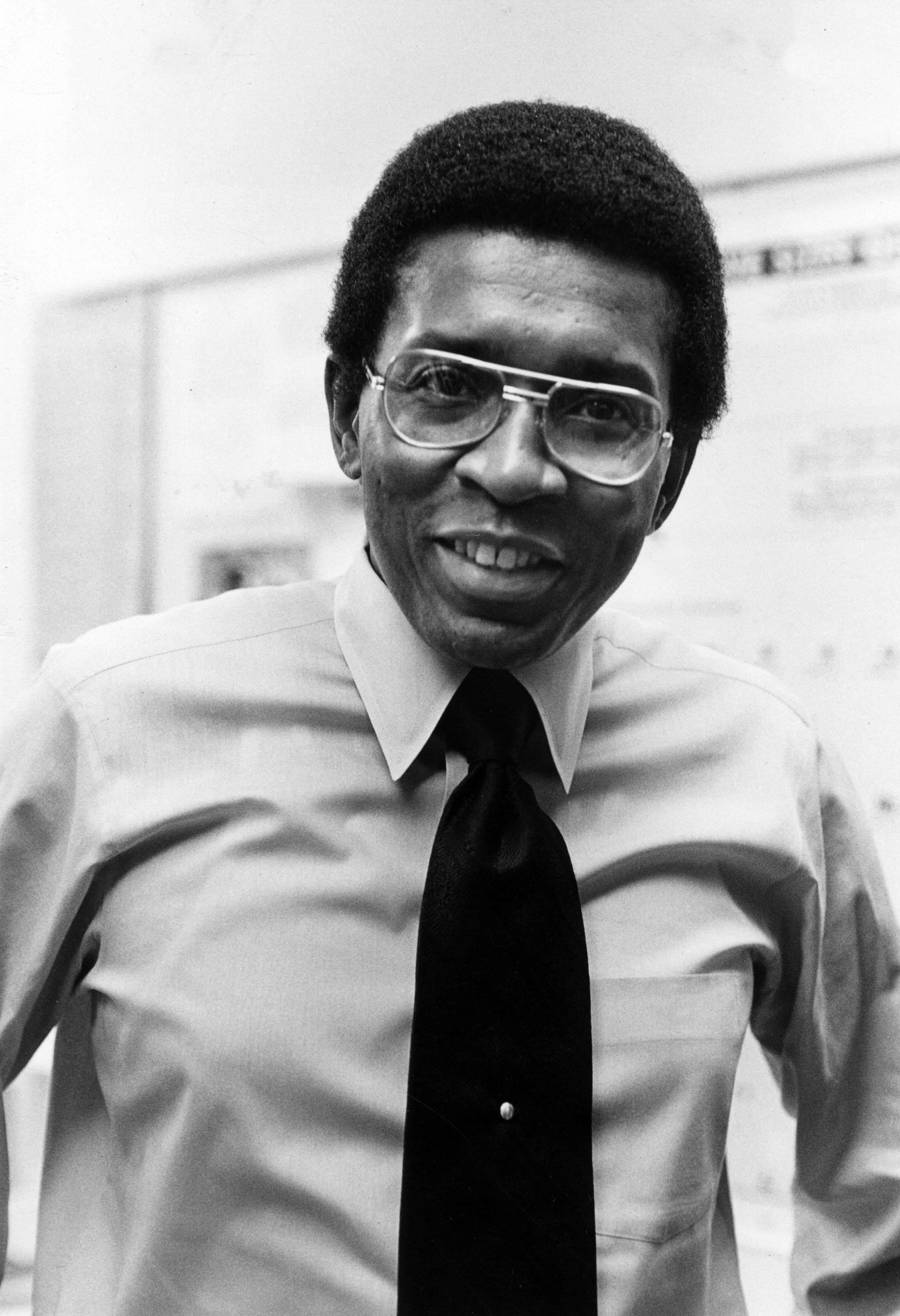 A black and white portrait of a man wearing glasses.
