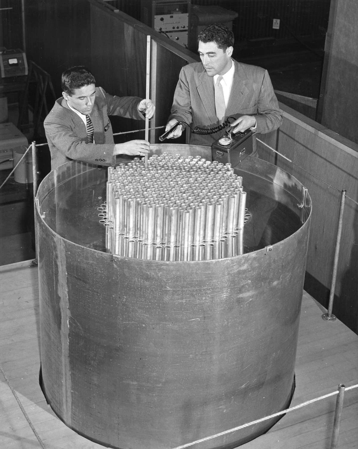 Two men engaged in hands-on work with a large metal object.