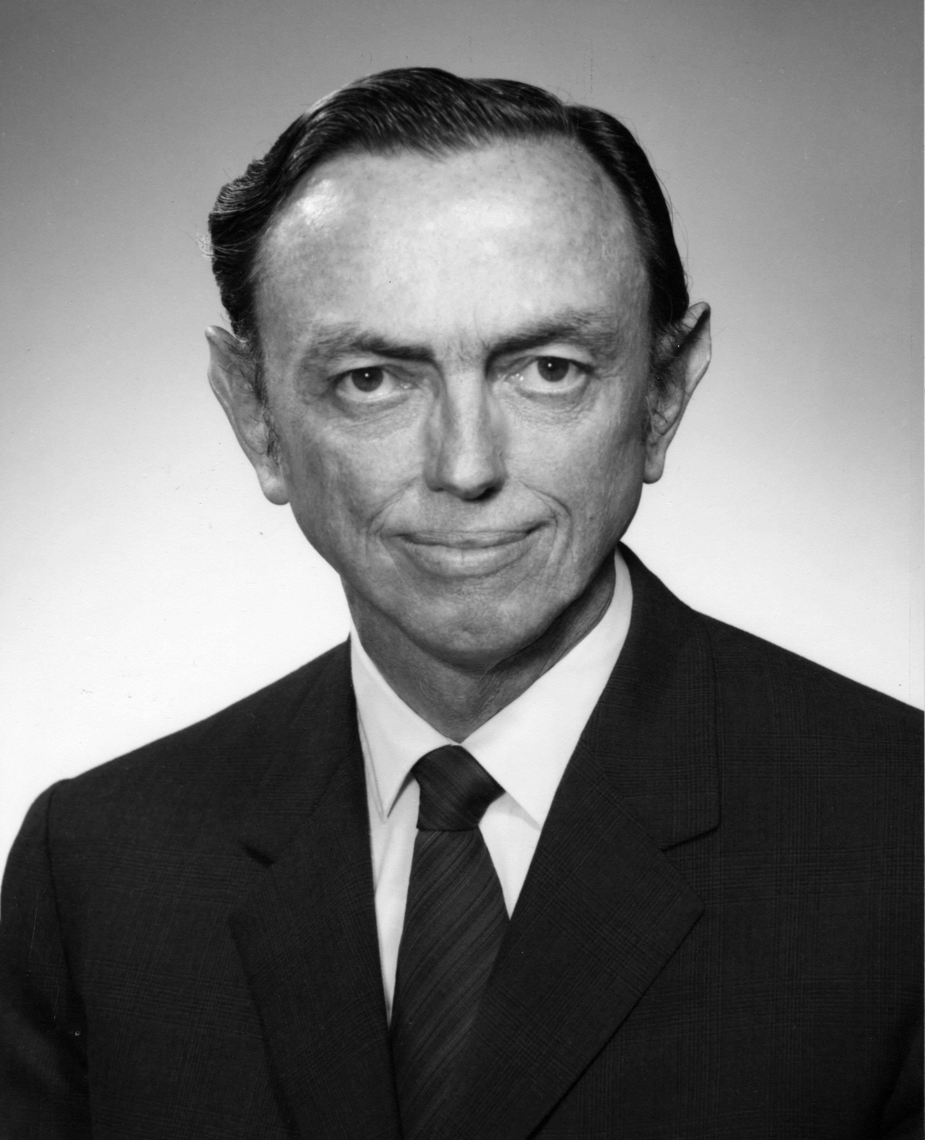 A black and white portrait of a man wearing a suit and tie.