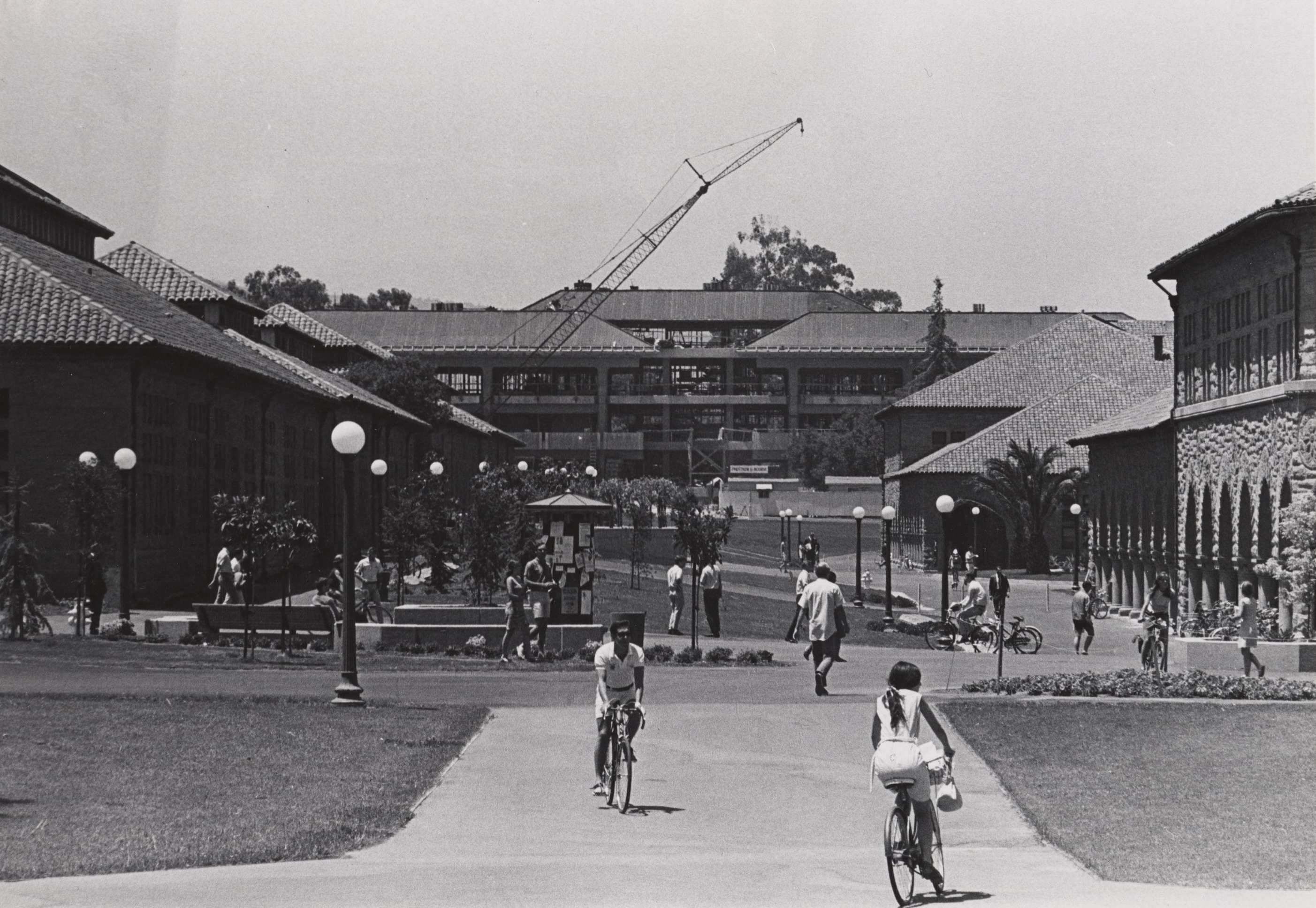 An old black and white image featuring individuals cycling and walking around.