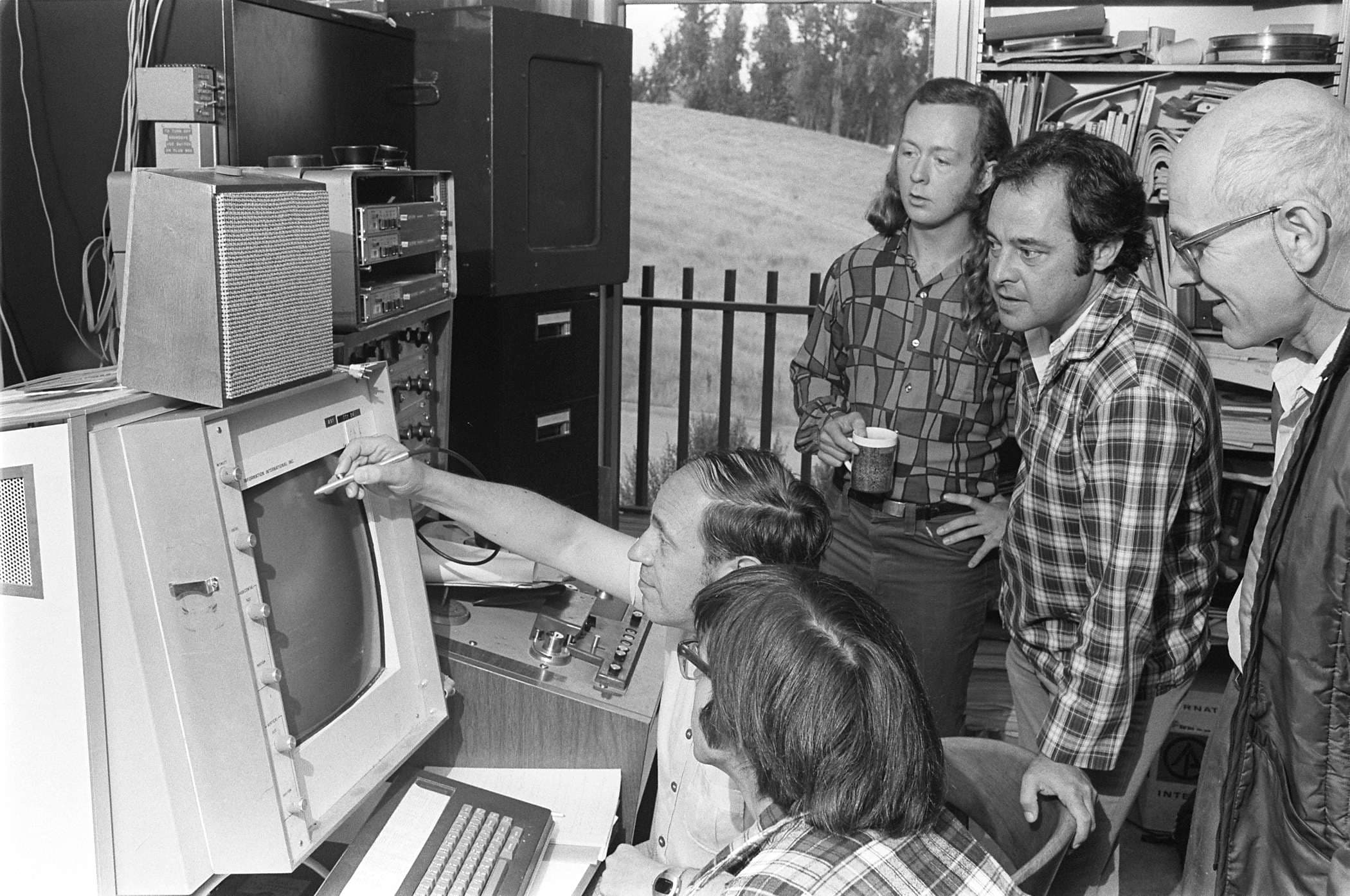 Several people focused on a computer screen, engaged in discussion and collaboration.