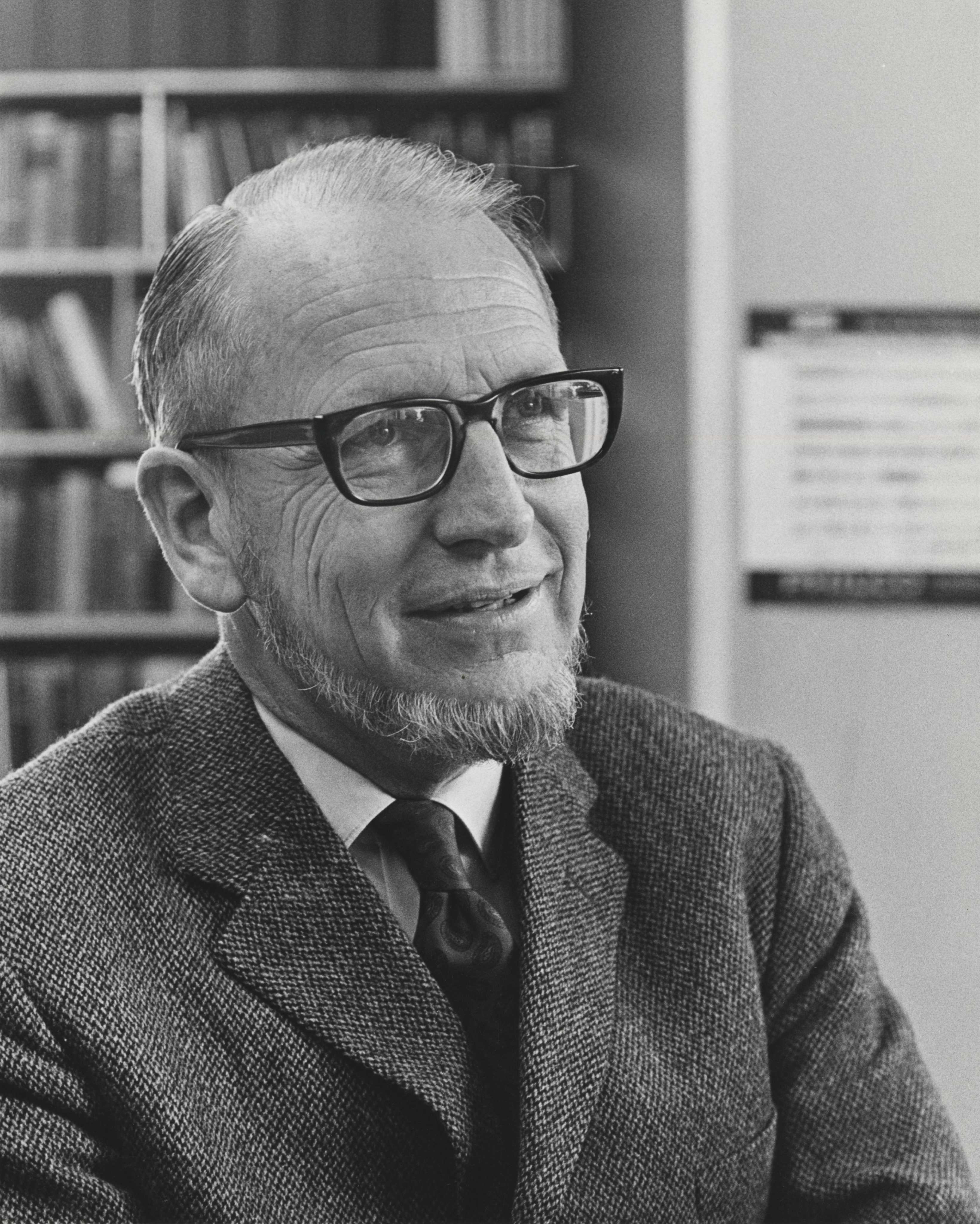 A black and white portrait of a man wearing glasses.