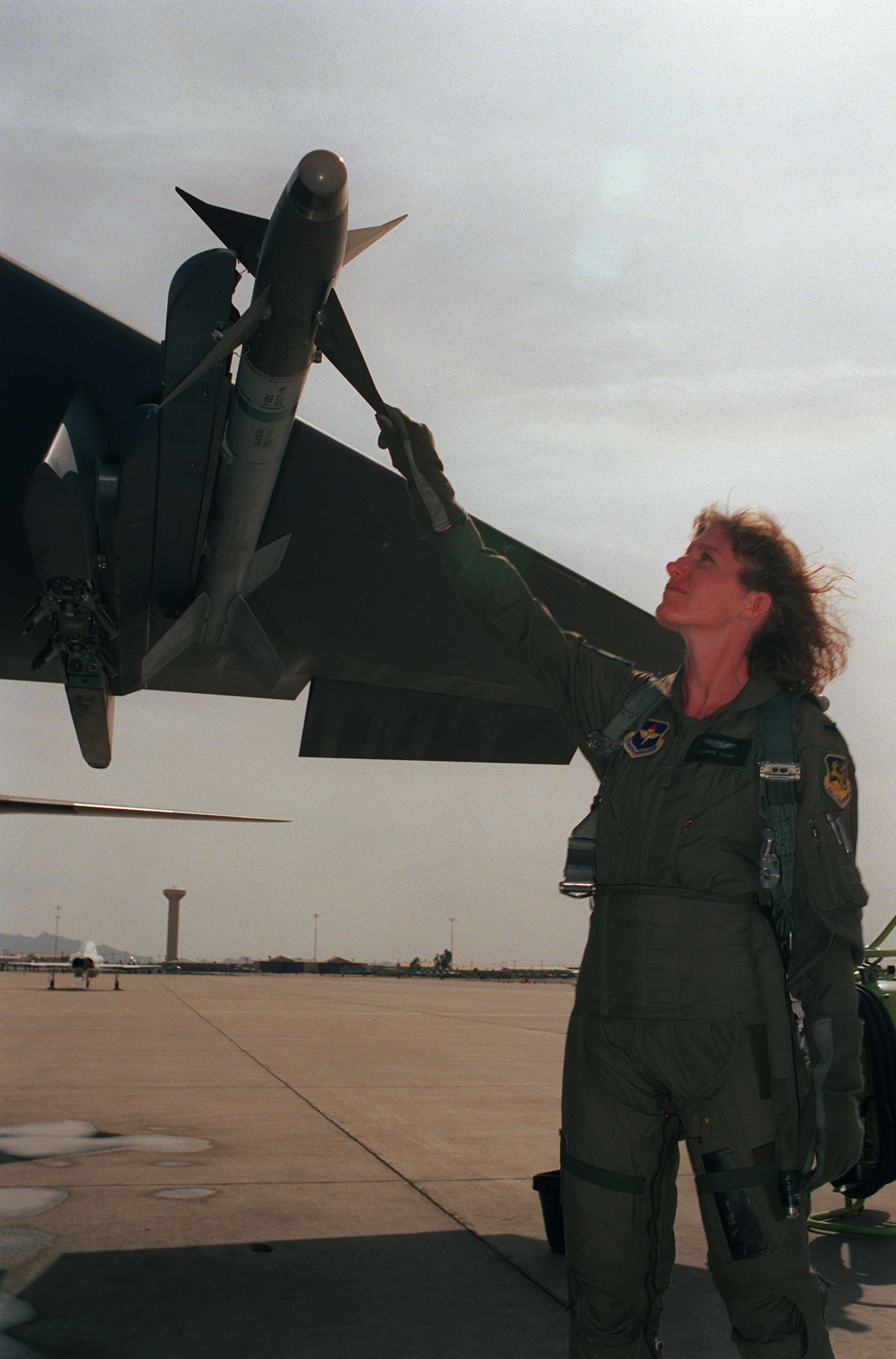 A woman in a flight suit, touching a piece of the plane.
