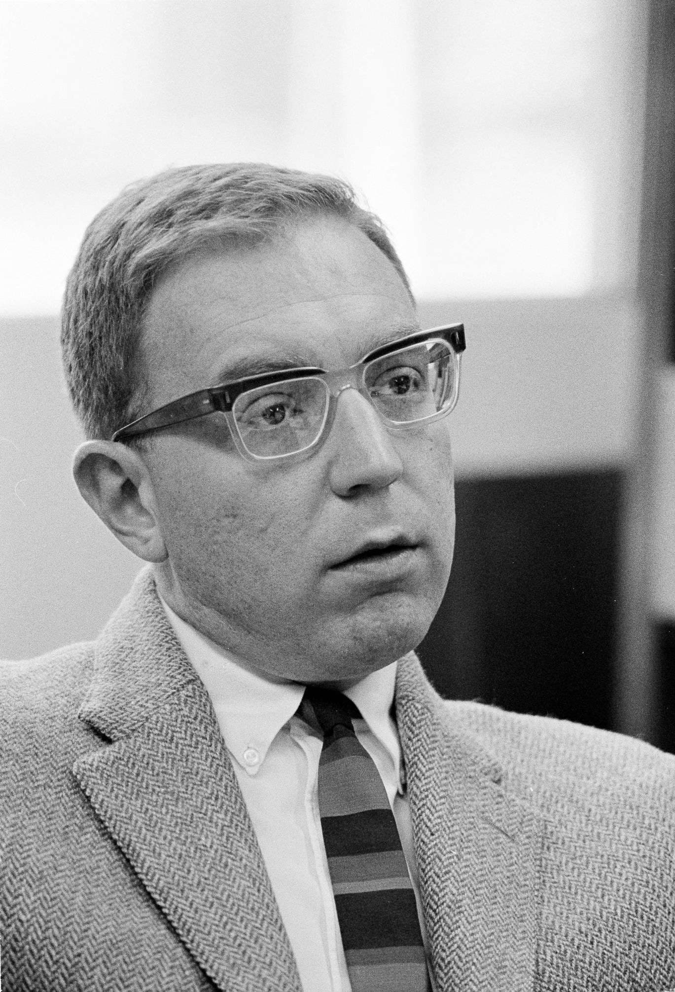 A man in a suit jacket and glasses.