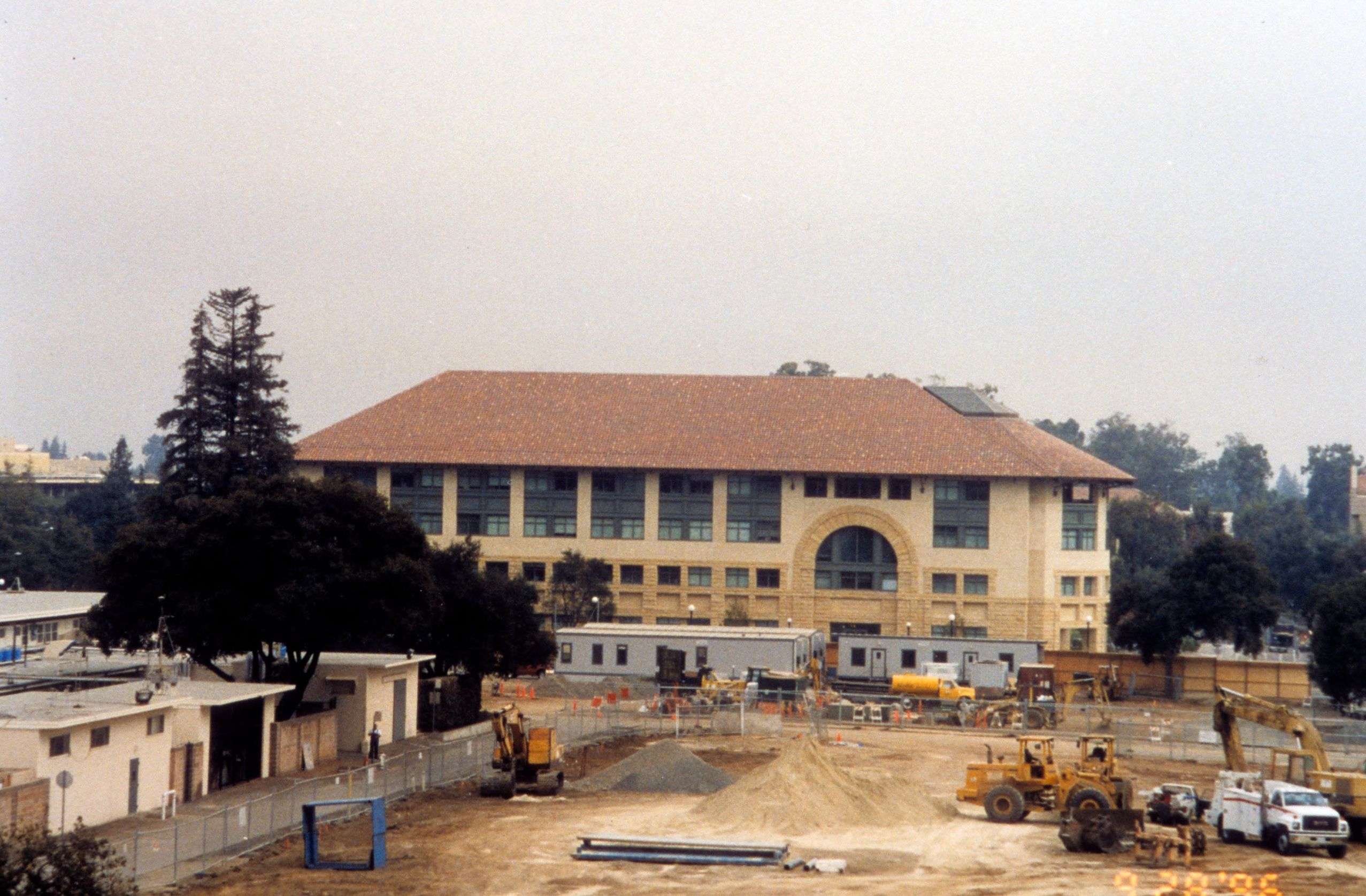A construction site featuring machinery and workers, with a building visible in the background.