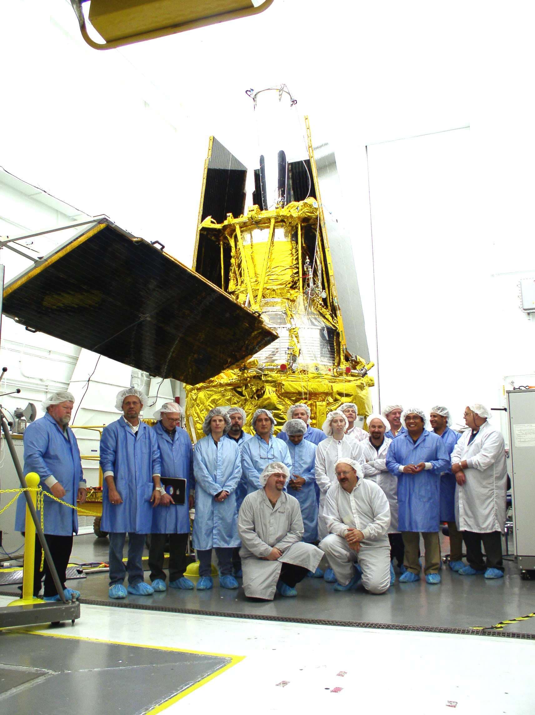 A group of people, standing in front of an object.