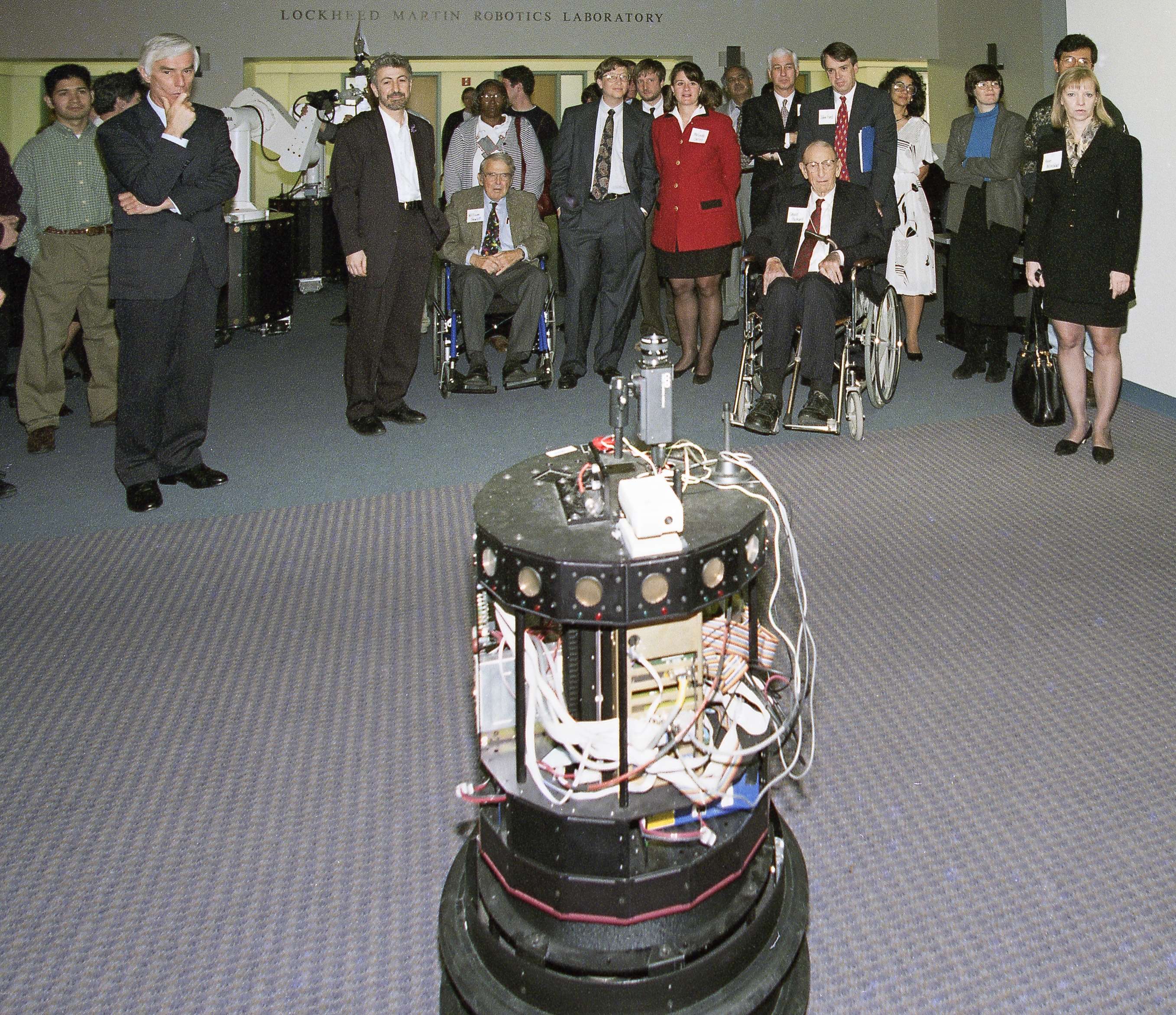 A group of people gathered around a robot.