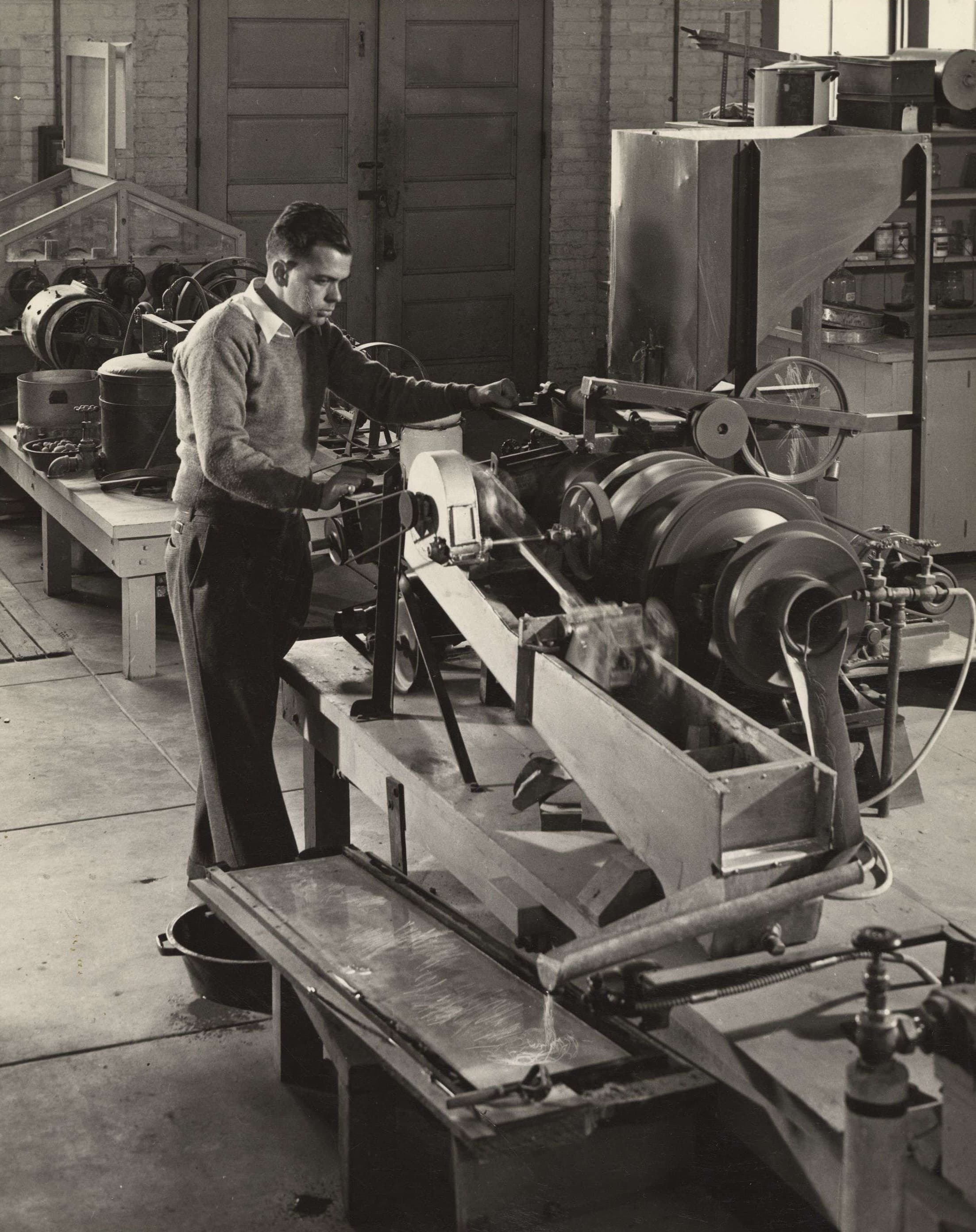 A factory worker engages with a miniature ore-treating plant in a mining lab