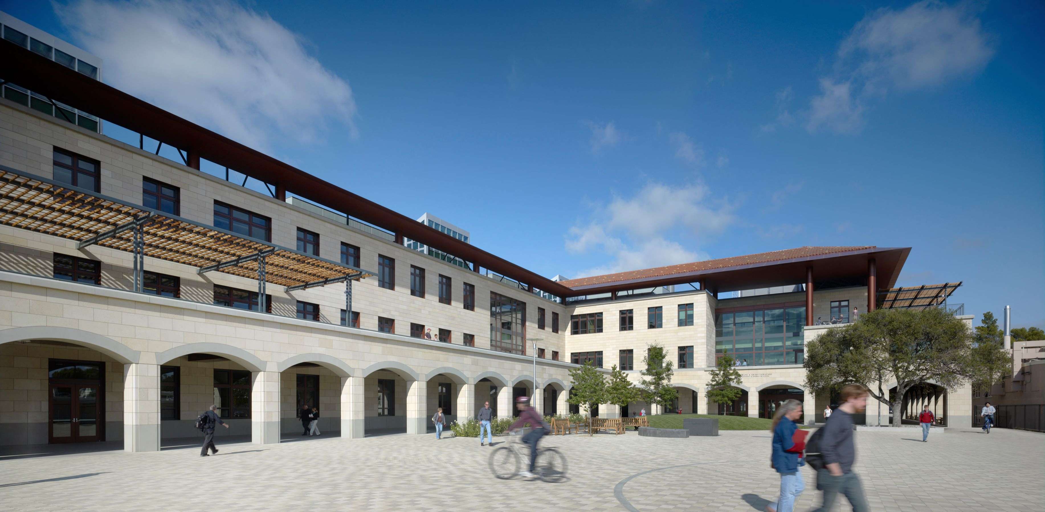 People walking and cycling in front of a building.