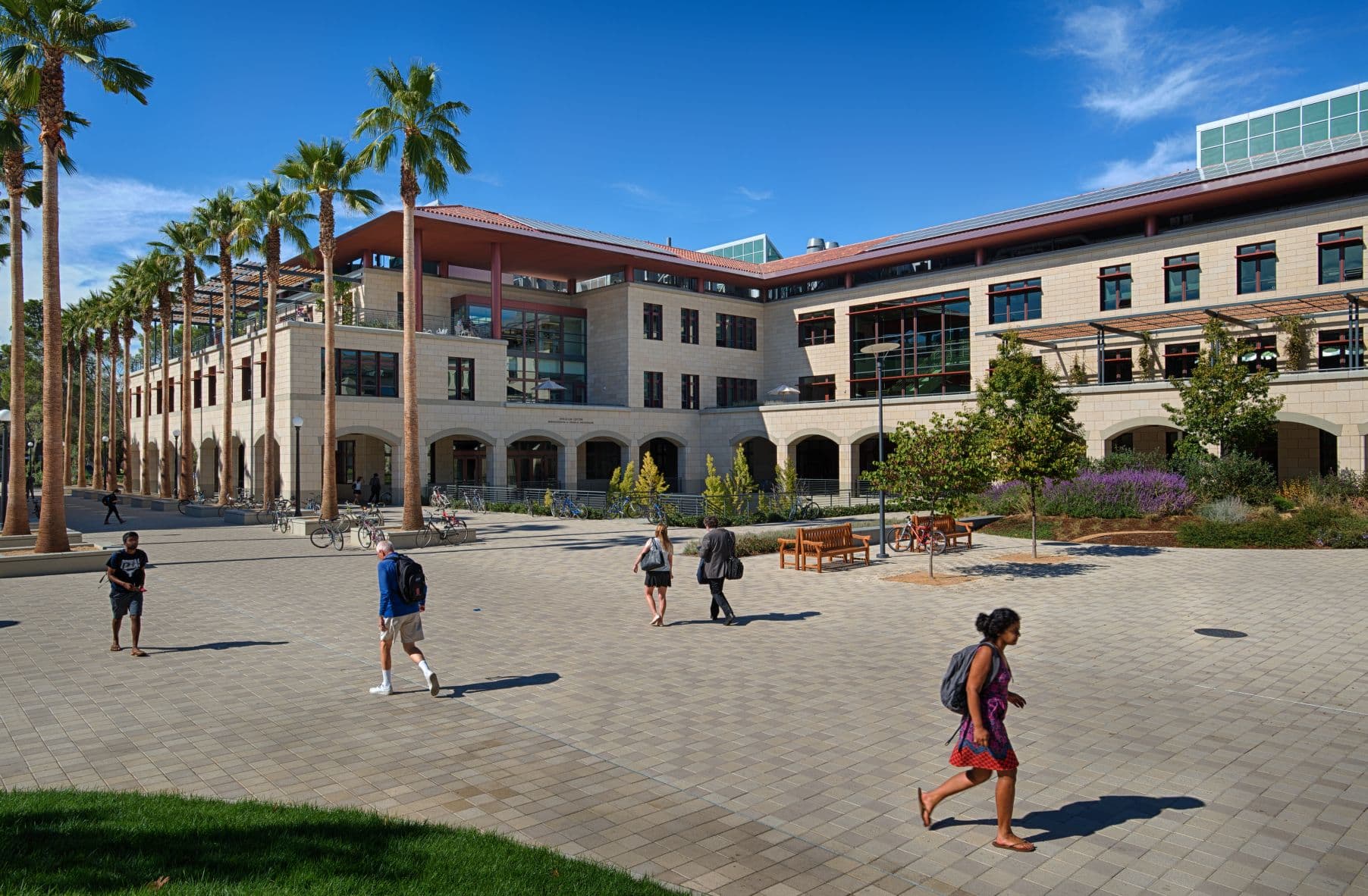 A group of people strolls through a courtyard in front of a building.
