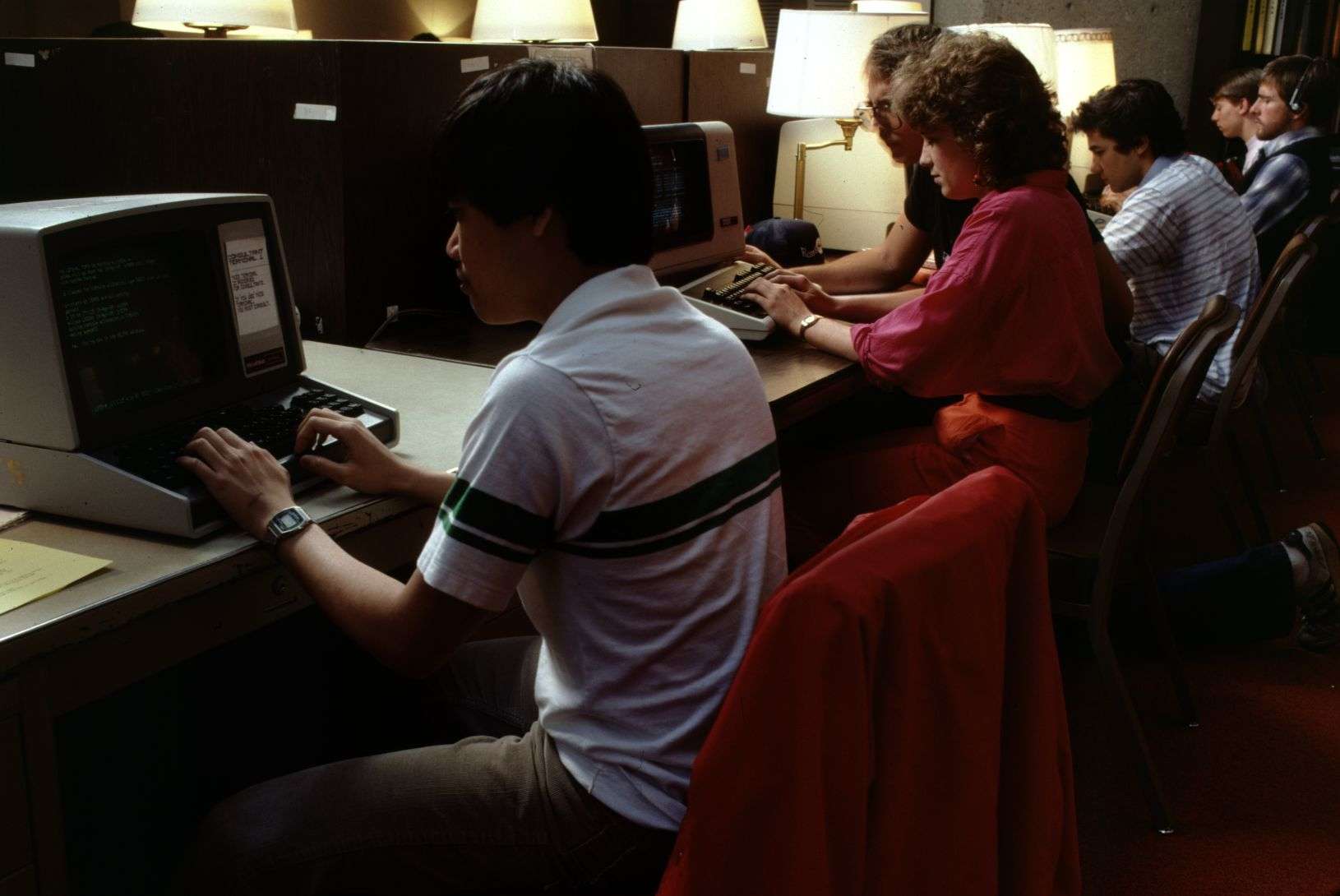 A diverse group of individuals focused on their computers while seated at tables.