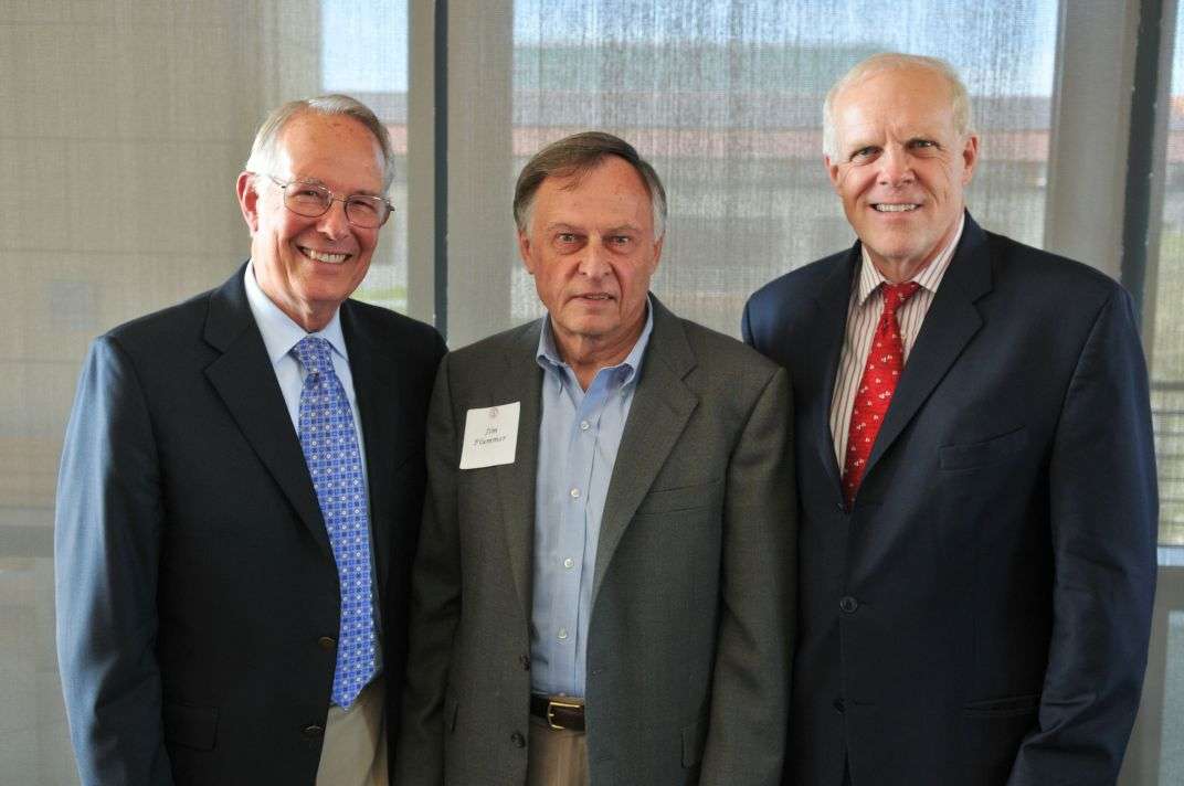 Three men in suits standing side by side.