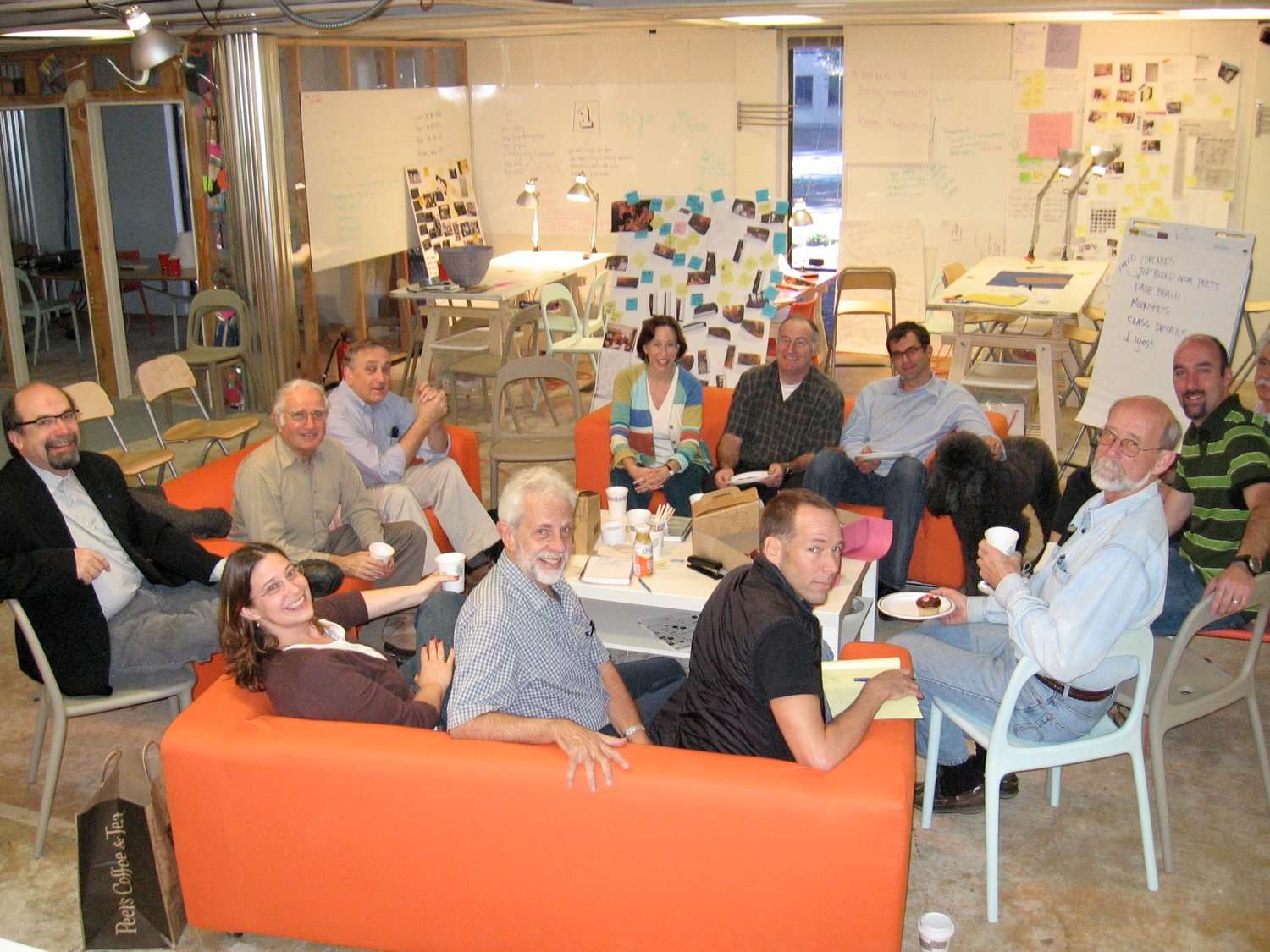 A group of individuals seated on vibrant orange couches.