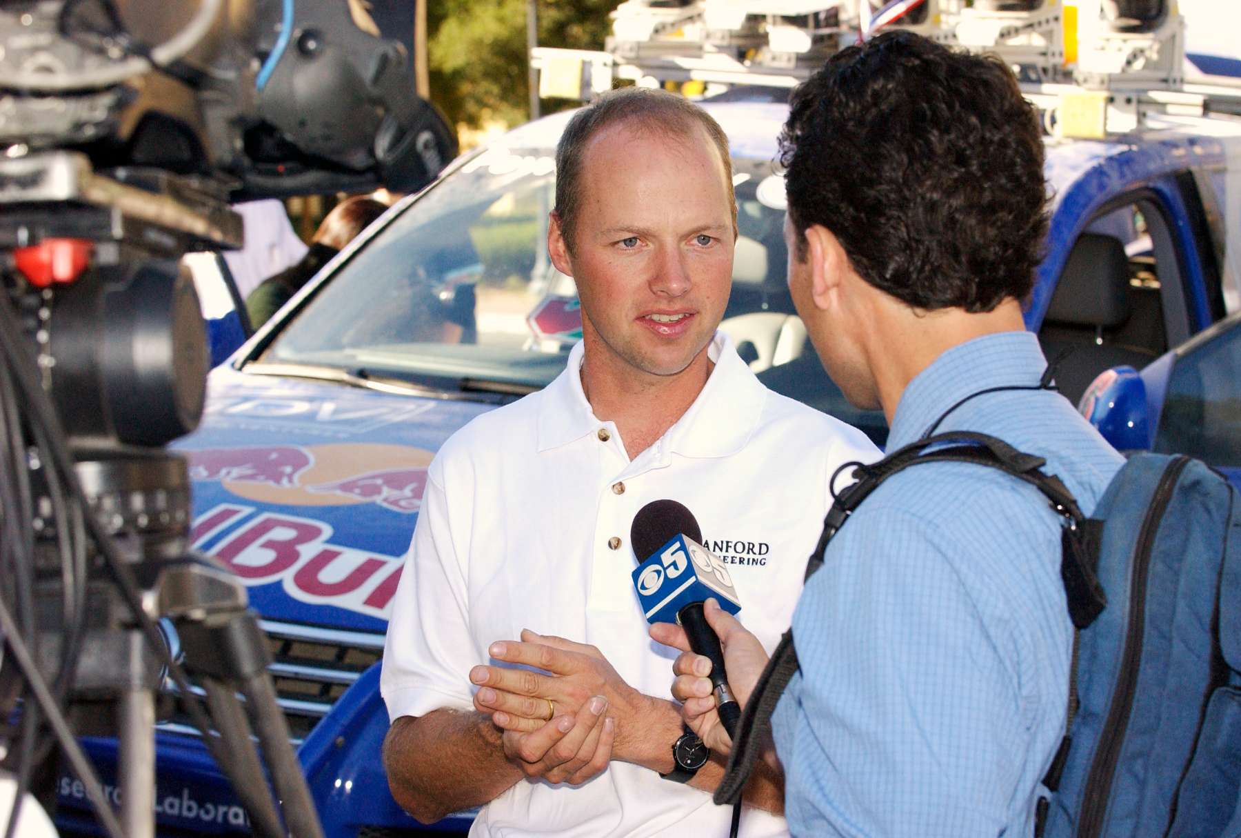 A man in a white shirt engages in conversation with a reporter.