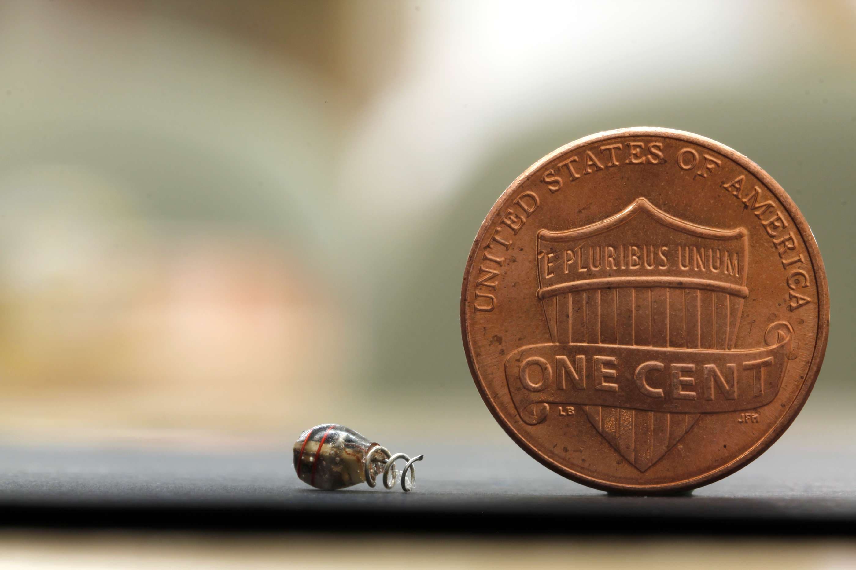 Tiny bug-like robot positioned beside a U.S. penny.