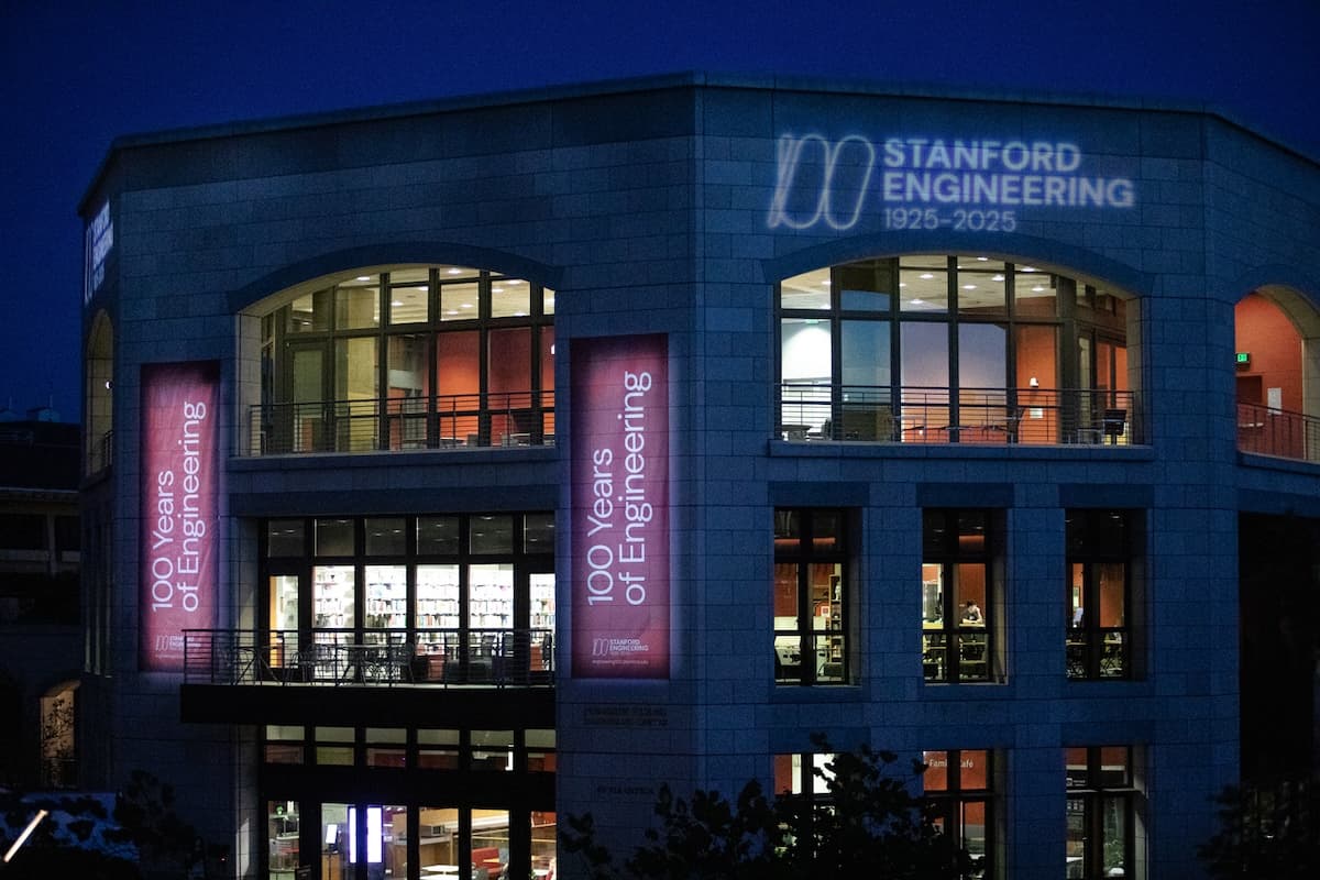 Nighttime view of the Stanford Engineering building, with banners and a project Stanford Engineering 1925–2025 sign